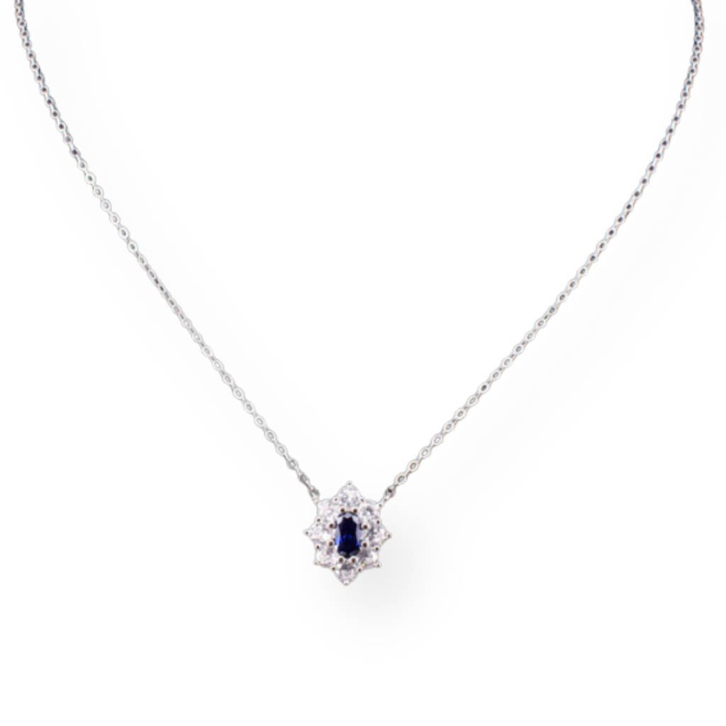 Collana in oro bianco con pendente a fiore di zaffiro e diamanti, su sfondo bianco.
