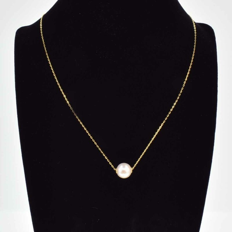 Collana in oro con catena sottile e una singola perla bianca. Il gioiello è esposto su un busto di velluto nero.