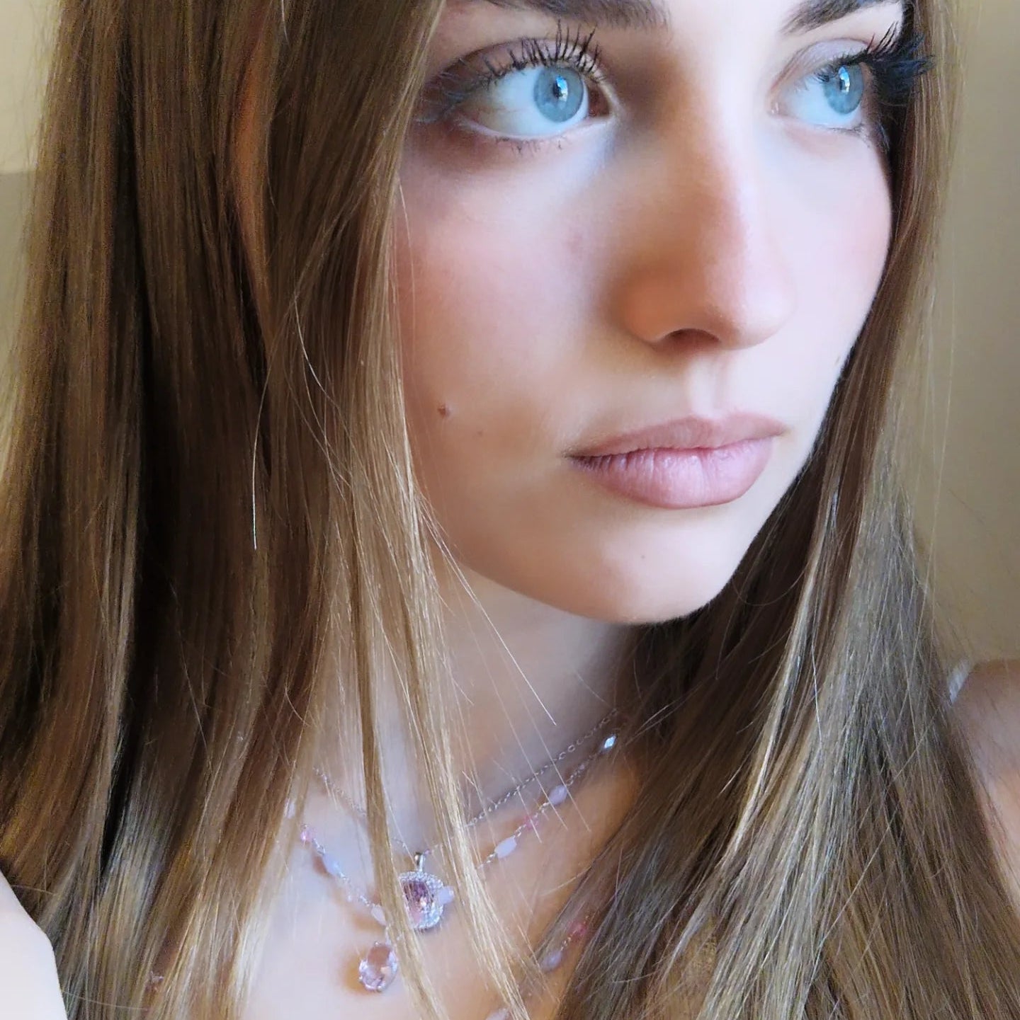 Primo piano di una giovane donna con luminosi occhi azzurri e capelli chiari, che guarda di lato.