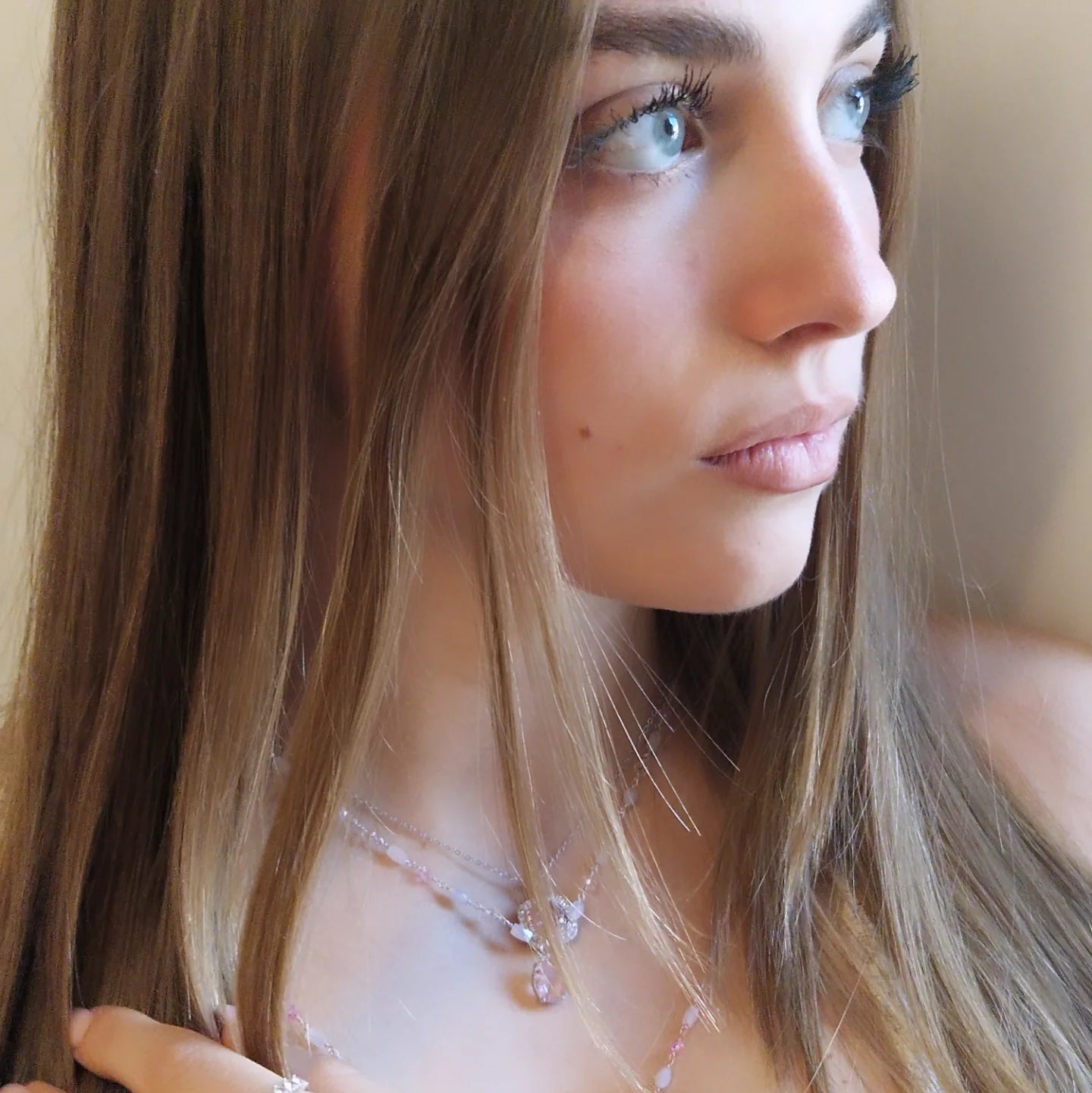 Ritratto di donna con capelli castani e occhi azzurri, indossa una collana rosa.