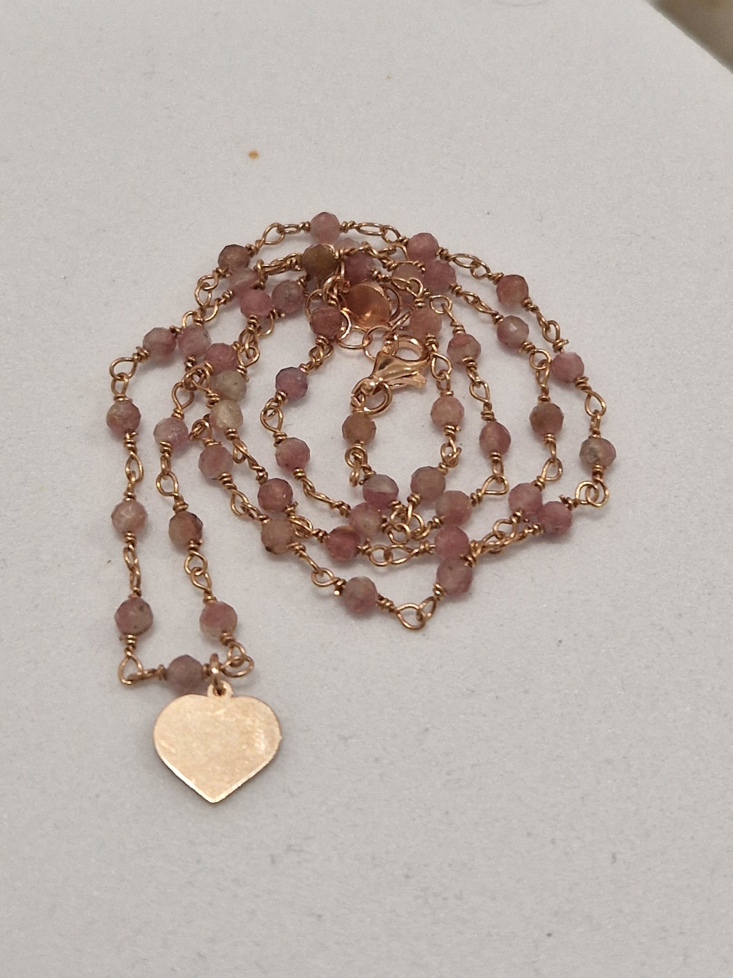 Collana in oro rosa con perle rosa e ciondolo a cuore.