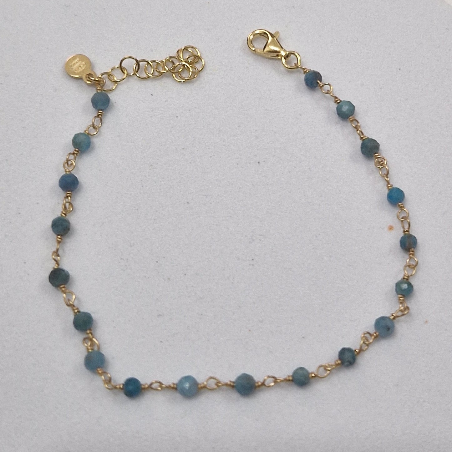 Braccialetto a catena d'oro con perline blu.