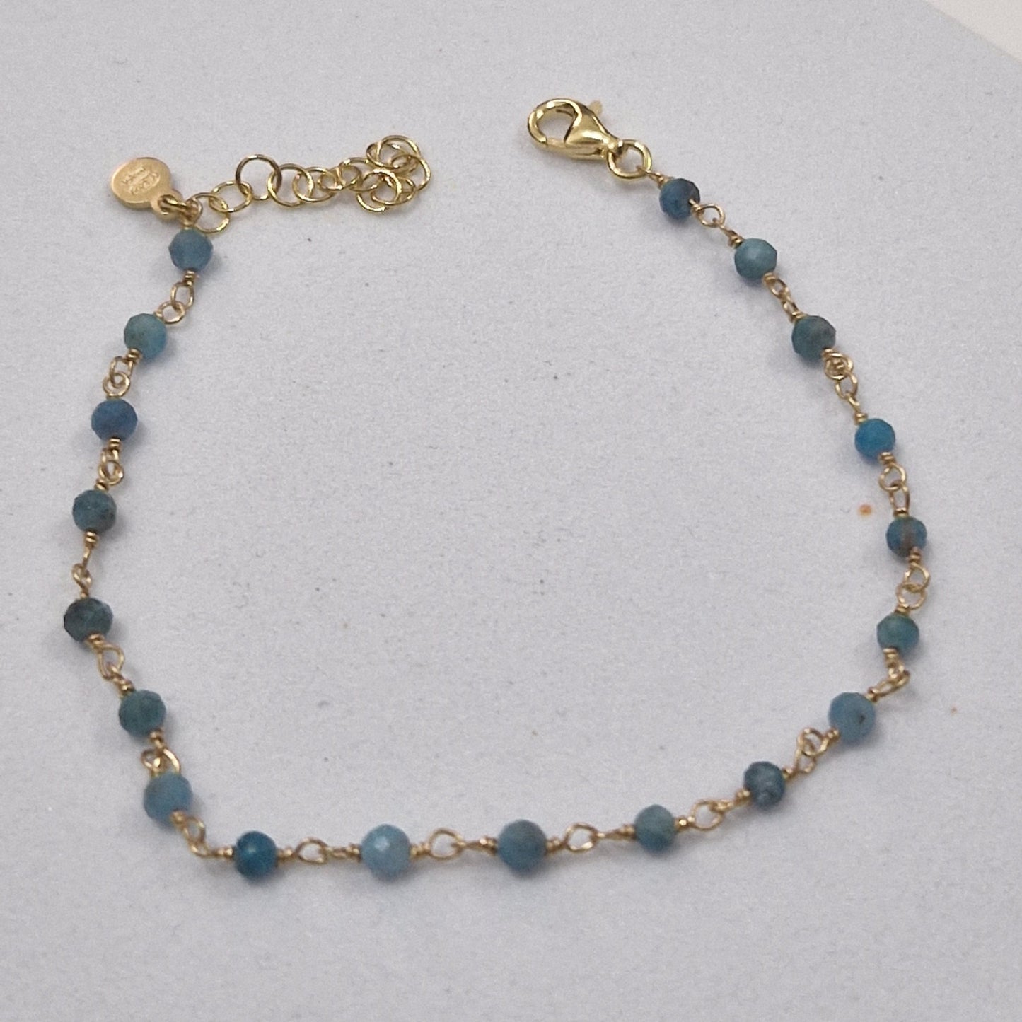 Braccialetto a catena d'oro con perline blu.