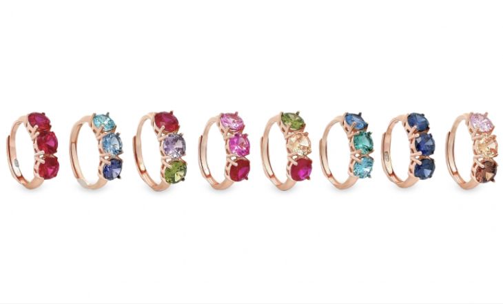 Trilogia di anelli in oro rosa con diverse combinazioni di pietre preziose colorate, ognuna con tre gemme.