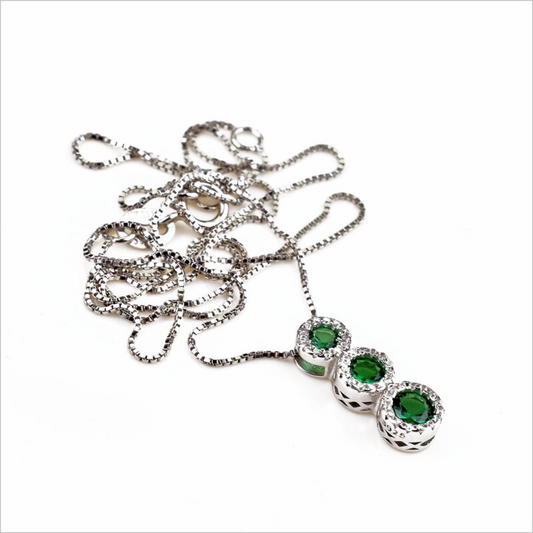 Collana in argento con tre ciondoli rotondi, ciascuno con una pietra verde smeraldo circondata da zirconi.