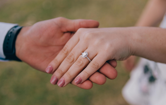 Uomo che tiene la mano di una donna che indossa un bellissimo anello, dimostrando eleganza e stile.