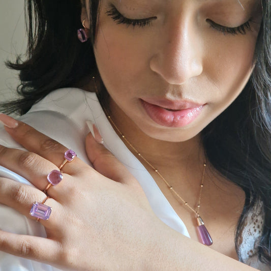 Ritratto di donna con gioielli di ametista: anelli, orecchini e una collana.