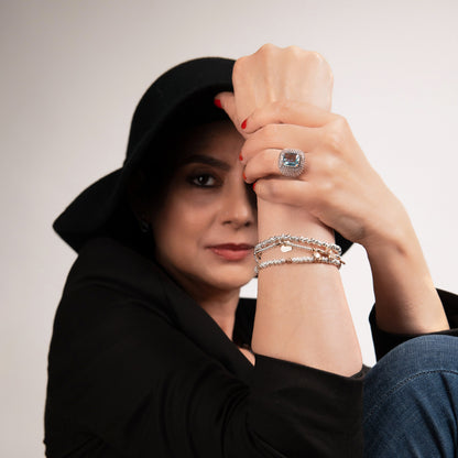 Donna elegante con cappello e anello grande, bracciali e unghie rosse, sguardo intenso.