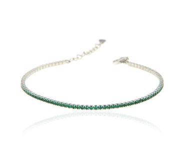 Bracciale tennis con smeraldi verdi incastonati in argento, visibile su sfondo bianco con riflesso.